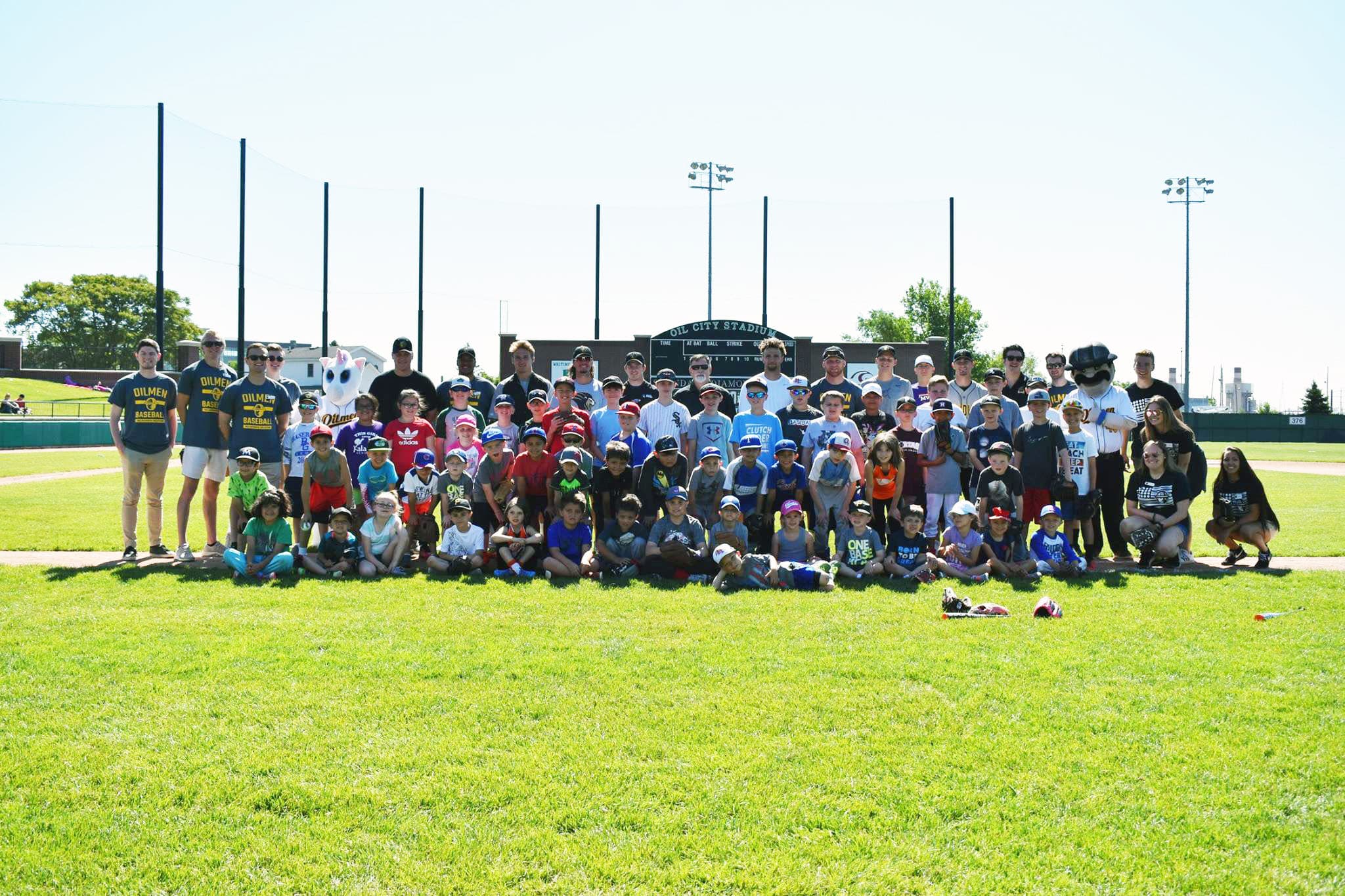 Youth baseball players and coaches posing for a group photo at Oil City Stadium.